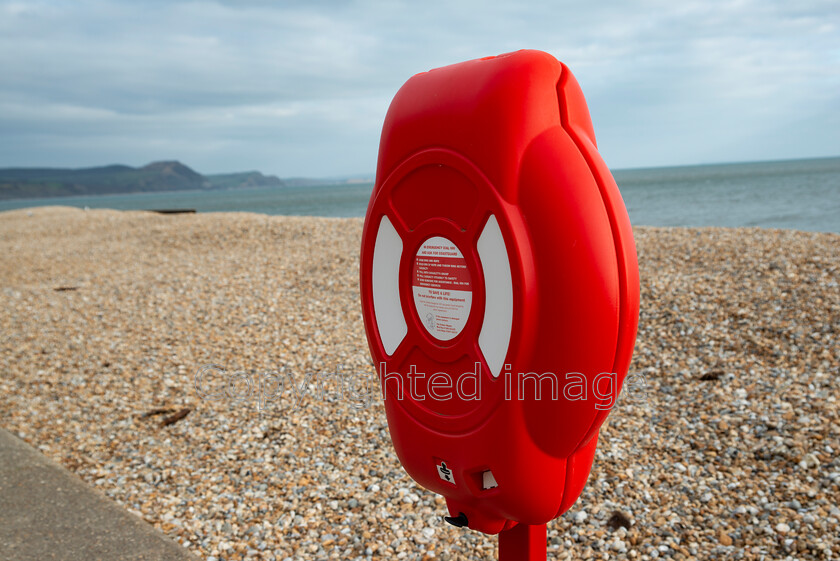 lyme-059 
 Lyme Regis and Uplyme riverside walk 
 Keywords: Lyme Regis, Uplyme, coastal town, Devon, Dorset, boarder, riverwalk, seaside, sea view, life saving equipment, life saver, bouyancy aid, red, bright, stoney beach, beach